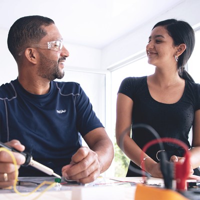 an older man and a younger woman share a moment of connection and pride after soldering a connection during the hands-on activity