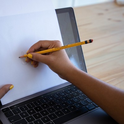during an icebreaker, a woman draws a shape with a pencil on a piece of paper placed on top of her laptop screen